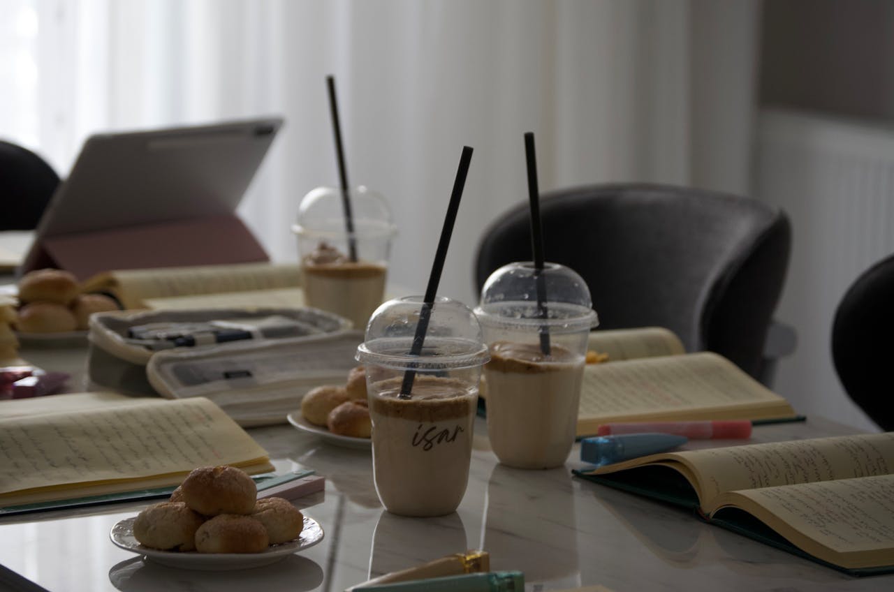 A minimalist workspace in Türkiye featuring coffee, snacks, and open notebooks, perfect for study or work.